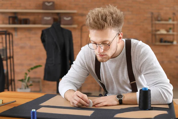 Young tailor working at table in atelier — Stock Photo, Image