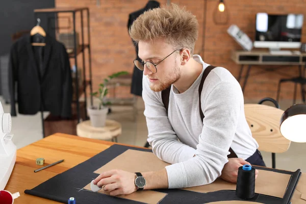 Young tailor working at table in atelier — Stock Photo, Image