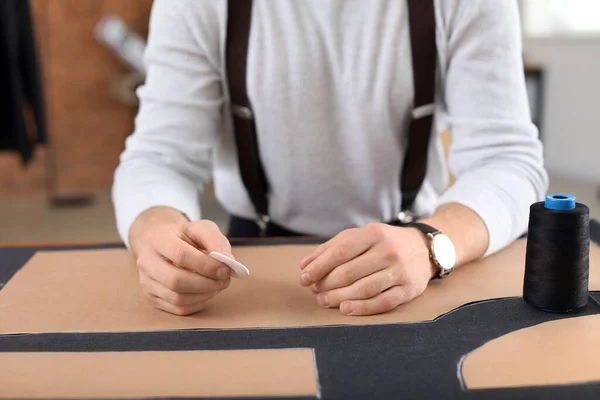 Joven sastre trabajando en la mesa en el taller, primer plano — Foto de Stock