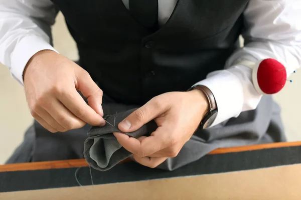 Young tailor working at table in atelier, closeup — Stok fotoğraf