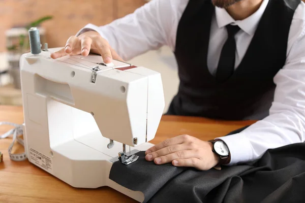 Young male tailor working on sewing machine in atelier — Stock Photo, Image