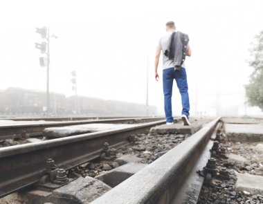 Young man going along railway track. Concept of choice