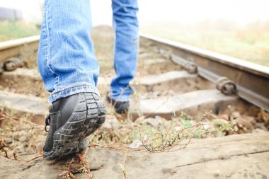 Young man going along railway track. Concept of choice