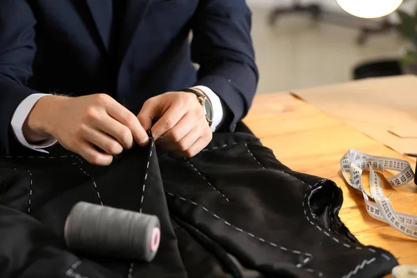 Young tailor working at table in atelier, closeup — Stok fotoğraf