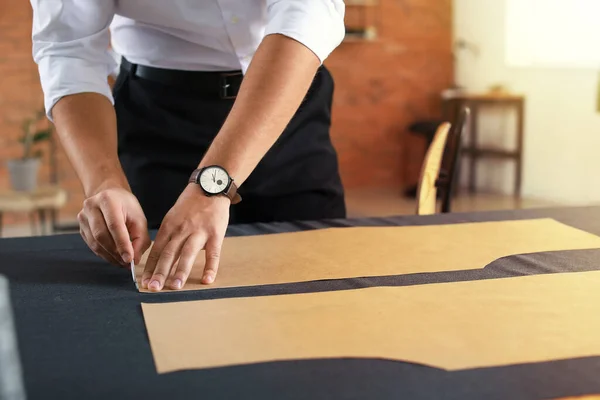 Νέος ράφτης που εργάζεται στο τραπέζι στο ατελιέ, κοντινό πλάνο — Φωτογραφία Αρχείου