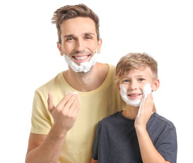 Father with son applying shaving foam onto their faces against white background