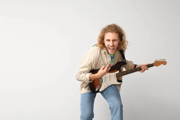 Емоційний чоловік грає на гітарі на світлому фоні — стокове фото