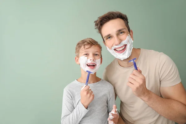 Father and his little son shaving against color background — Stock Photo, Image