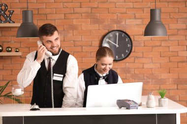 Male and female receptionists working at desk in hotel