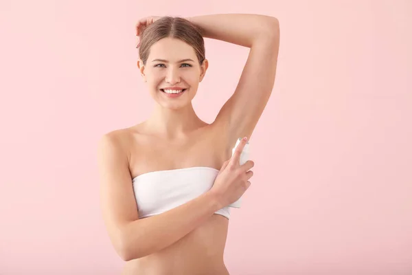 Beautiful young woman using deodorant on color background — Stock Photo, Image