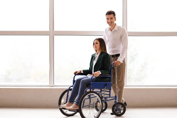 Handicapped young woman in wheelchair and her husband near window — ストック写真