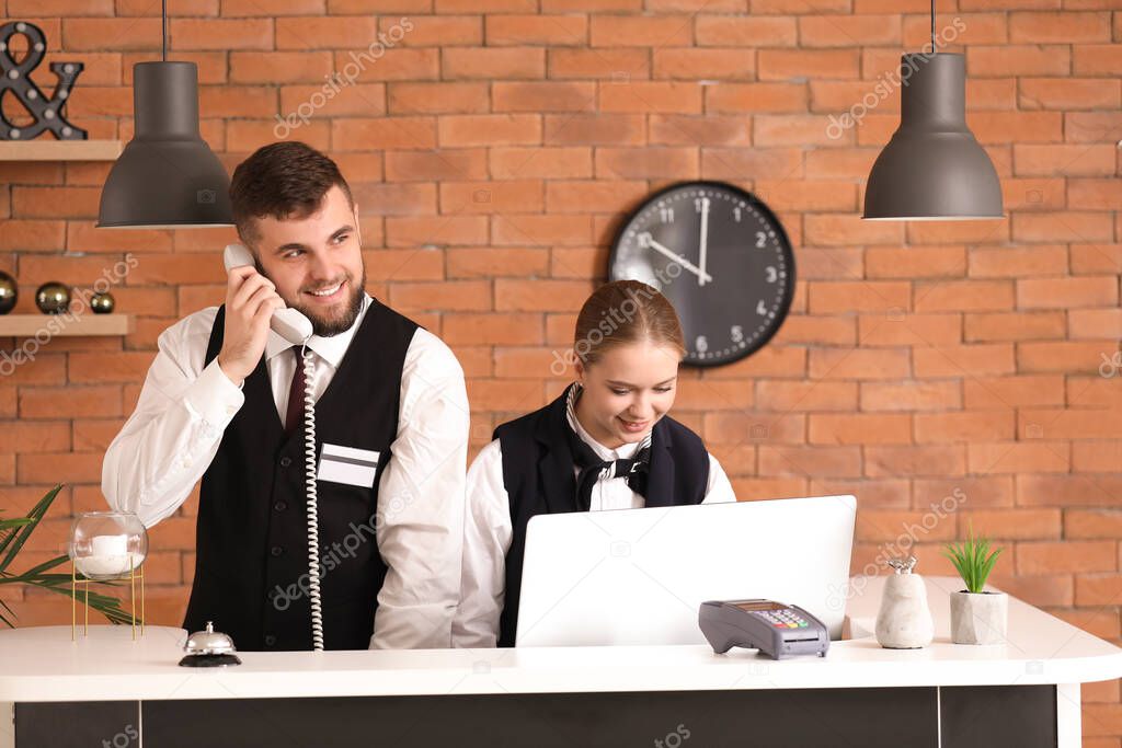 Male and female receptionists working at desk in hotel