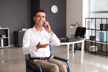 Handicapped young man talking by phone in office