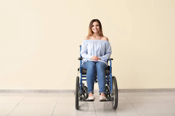 Jeune femme handicapée en fauteuil roulant près du mur de couleur — Photo