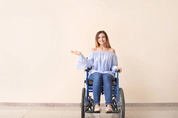 Jeune femme handicapée en fauteuil roulant près du mur de couleur — Photo
