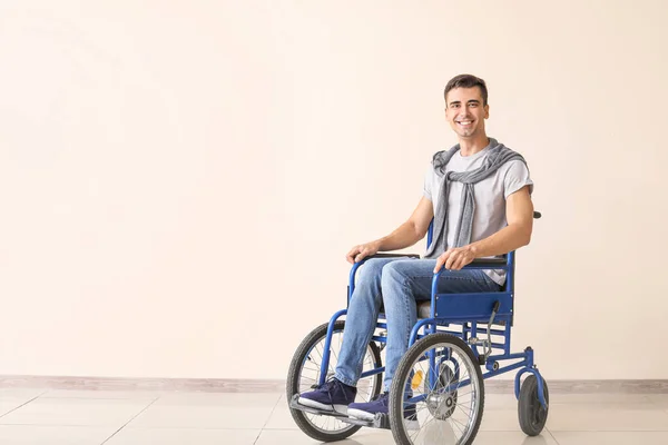 Młody niepełnosprawny mężczyzna na wózku inwalidzkim w pobliżu ściany koloru — Zdjęcie stockowe