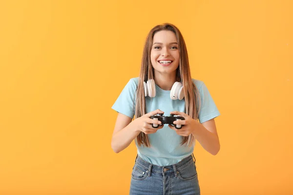 Young woman playing video game on color background — ストック写真