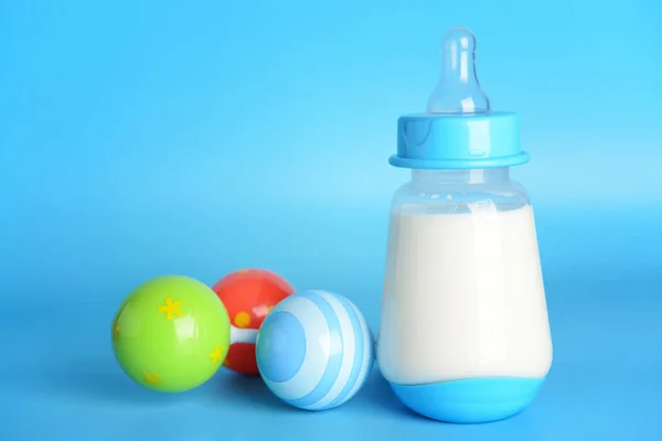 Bottle of milk for baby and toy on color background — Stock Photo, Image