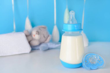 Bebek için bir şişe süt ve masada emzik.