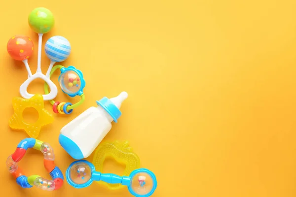 Bottle of milk for baby and toys on color background — Stock Photo, Image