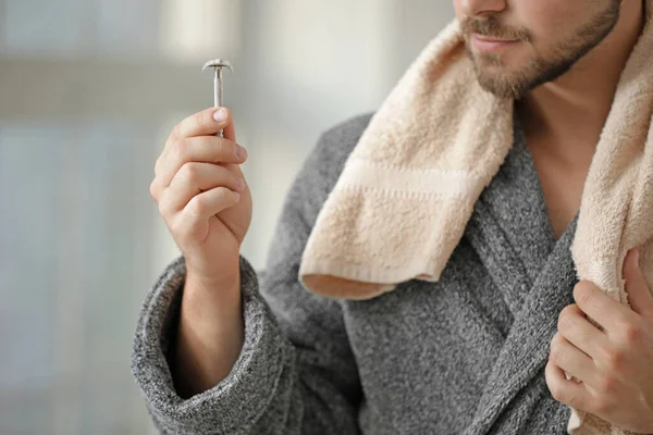 Knappe jongeman met handdoek en scheermes in de badkamer — Stockfoto