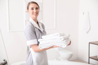 Otel banyosunda temiz havluları olan güzel oda hizmetçisi.