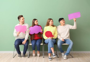 Renk duvarının yanında boş konuşma baloncukları olan bir grup genç.