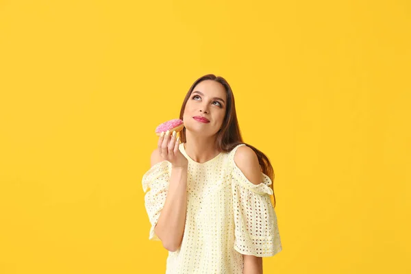 Mooie jonge vrouw met donut op kleur achtergrond — Stockfoto