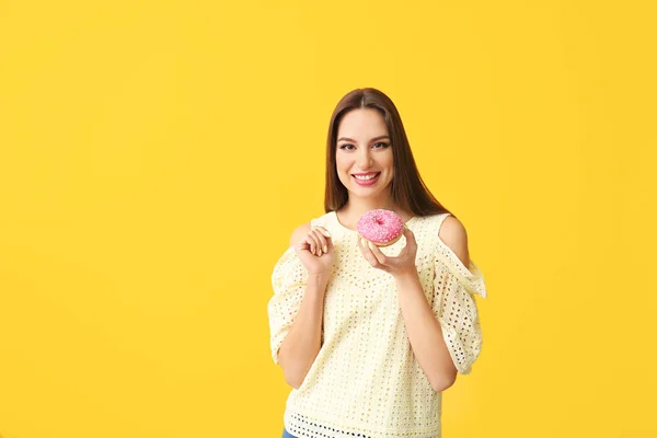 Όμορφη νεαρή γυναίκα με ντόνατ στο φόντο χρώμα — Φωτογραφία Αρχείου