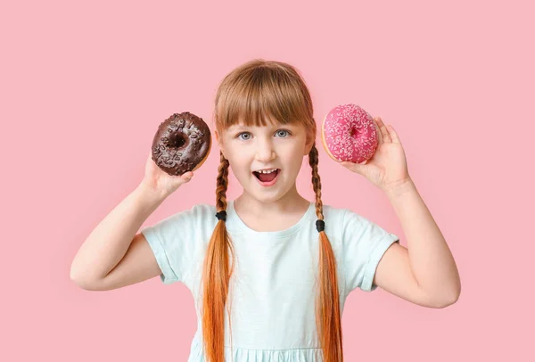 Funny little girl with donuts on color background — Stock Photo, Image