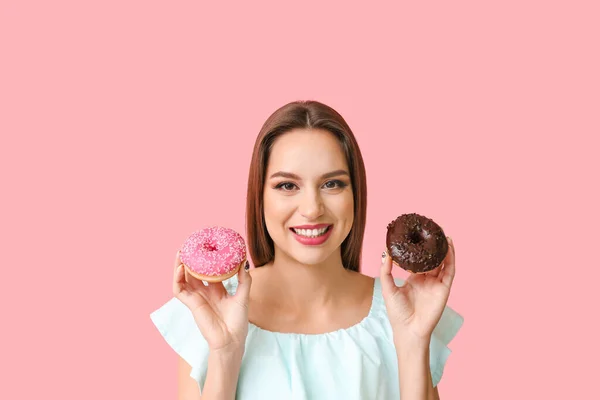 Beautiful young woman with donuts on color background — Stock Photo, Image