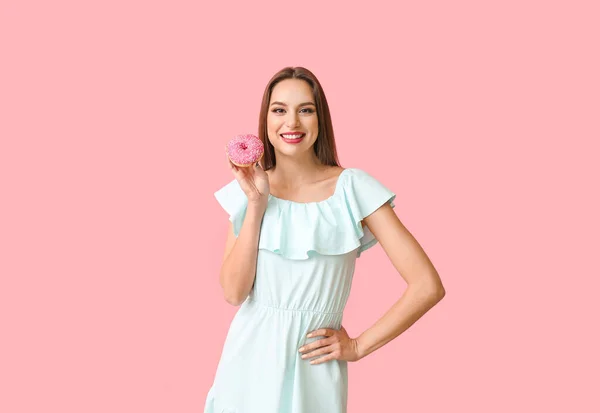 Hermosa joven con rosquilla en el fondo de color —  Fotos de Stock