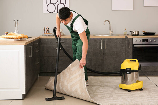 Asian janitor hoovering floor in kitchen