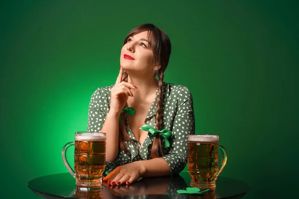 Jeune femme drôle avec de la bière à table sur fond de couleur. Célébration de la Saint Patrick — Photo