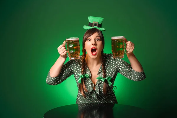 Jeune femme drôle avec de la bière à table sur fond de couleur. Célébration de la Saint Patrick — Photo