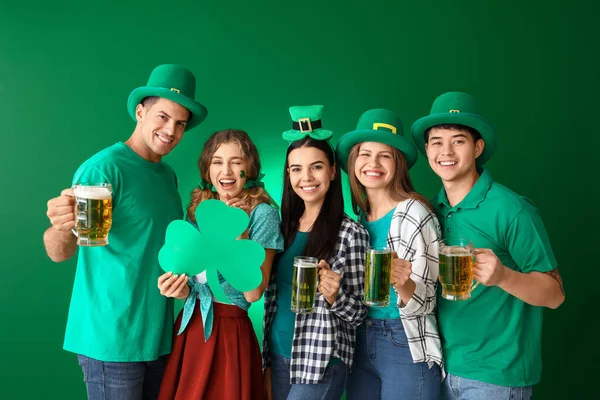 Vrienden met bier en klaver op kleur achtergrond. St. Patrick 's Day viering — Stockfoto