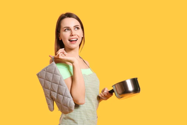 Young housewife with kitchenware on color background — Stock Photo, Image