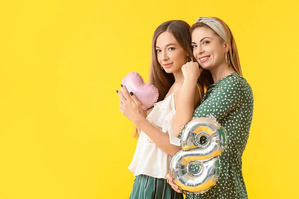 Vackra unga kvinnor med gåvor på färg bakgrund. Internationella kvinnodagen firas — Stockfoto