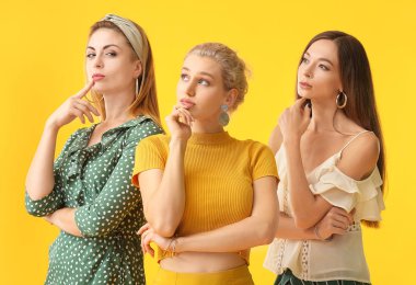 Beautiful thoughtful young women on color background