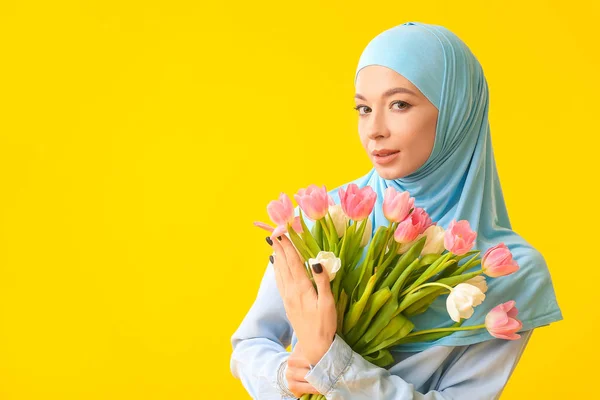 Mulher muçulmana bonita com flores no fundo da cor. Celebração do Dia Internacional da Mulher — Fotografia de Stock