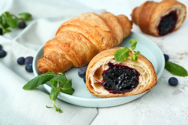 Plate with tasty sweet croissants on white background — Stockfoto