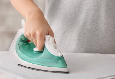 Kadın evde giysileri ütülüyor, yakın plan.