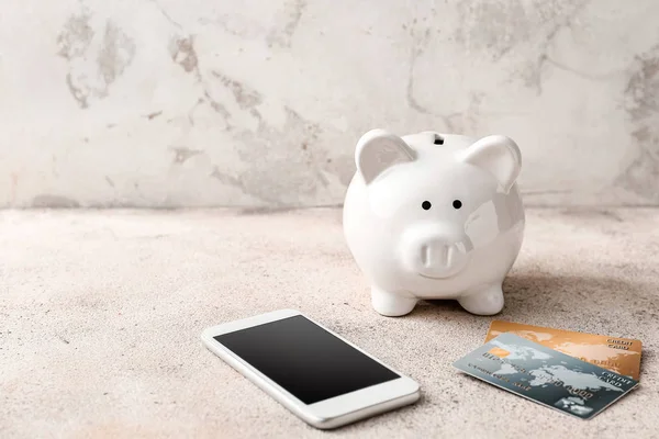 Credit cards with piggy bank and mobile phone on grey background. Concept of online banking — Stok fotoğraf