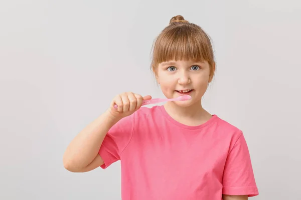 Mała dziewczynka ze szczoteczką do zębów na jasnym tle — Zdjęcie stockowe