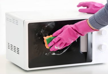 Woman cleaning microwave oven in kitchen