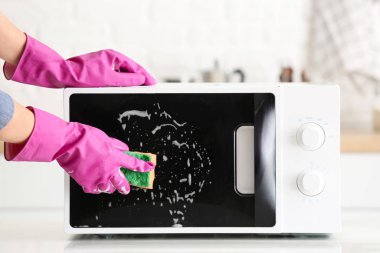 Woman cleaning microwave oven in kitchen