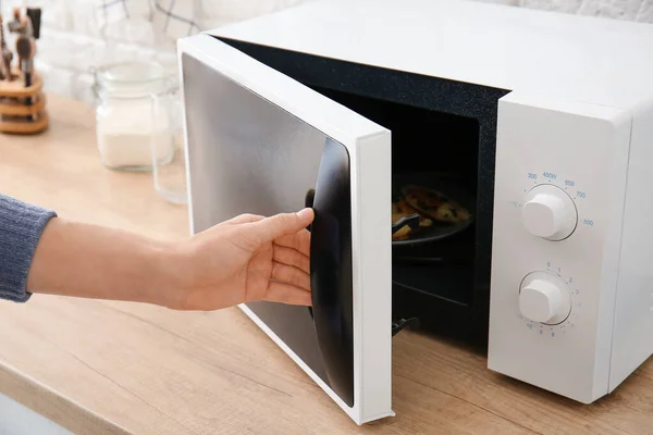 Woman opening modern microwave oven in kitchen — Stock Photo, Image