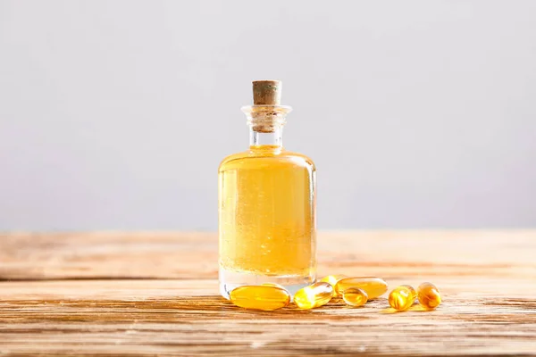 Bottle of fish oil and capsules on wooden table — Stock Photo, Image