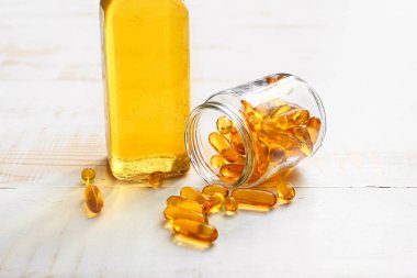 Bottle of fish oil and capsules on wooden table