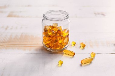 Jar of fish oil capsules on wooden background